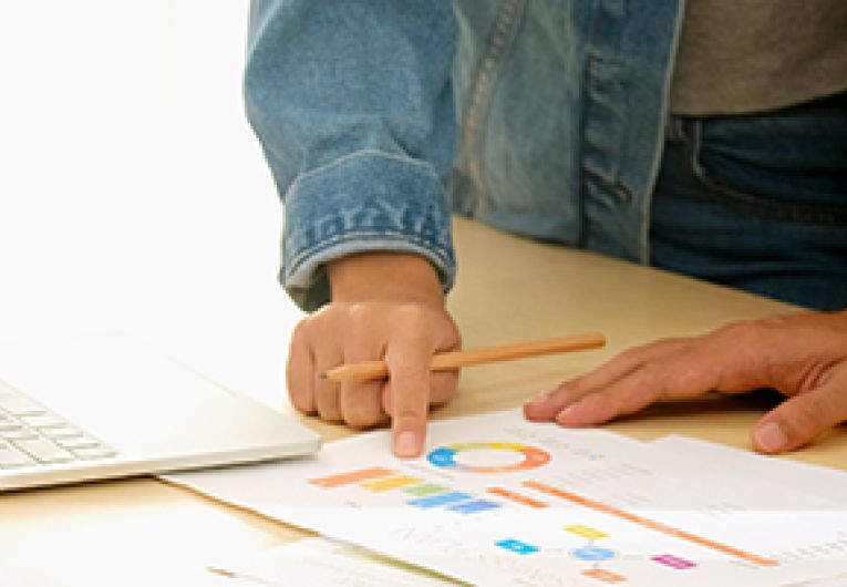 Two people standing next to each other looking over a report.