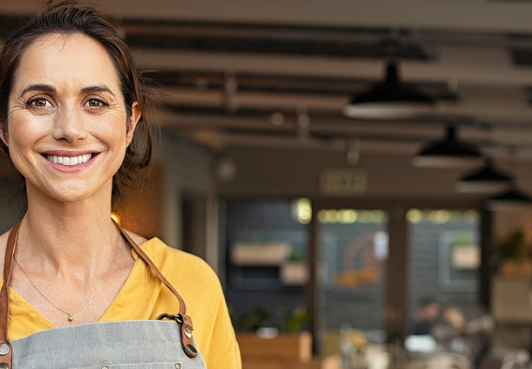 Female small business owner smiling in front of store.