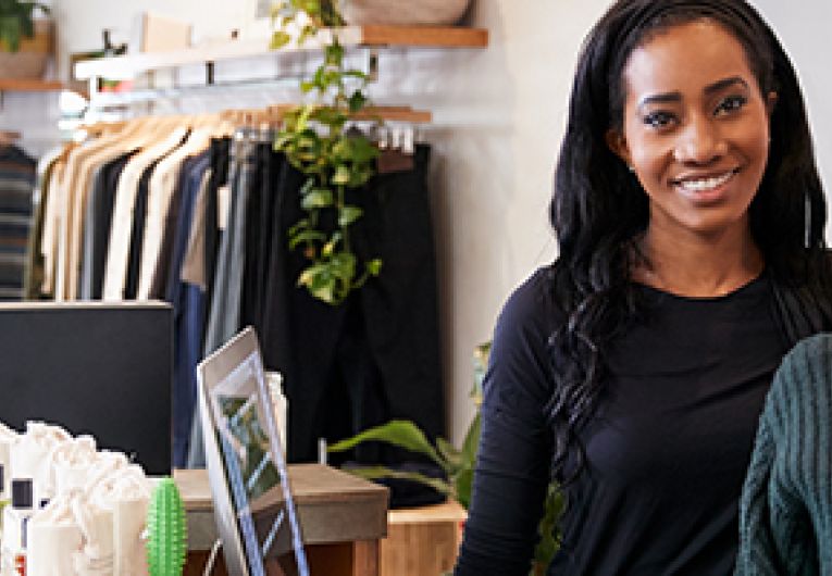 Two business owners smile while at the cash register in a store.