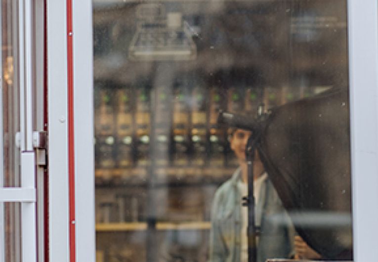 Female Entrepreneur stands by the door of her coffee shop.