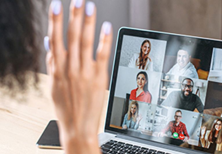 Small Business owner waves in a video conference call with staff.