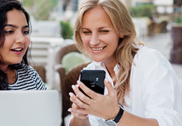 Two business owners take a break from work to look at a mobile device.