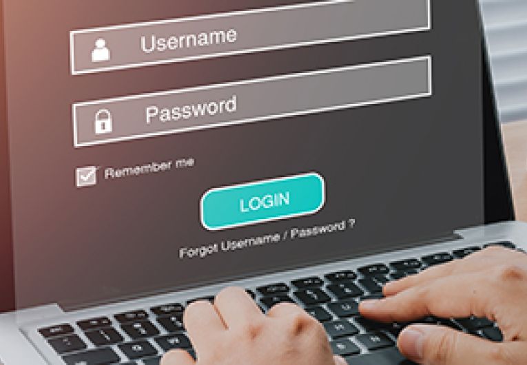 A small business owner typing in a username and password at a laptop.