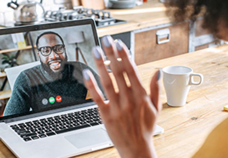 Job applicant waves at HR recruiter during a virtual hiring interview.