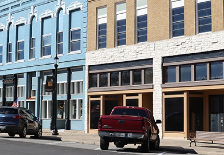 cars parked on rural downtown street in front of older 3-story buildings