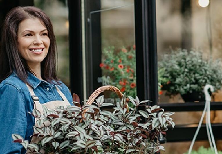 Small business owner with fresh flowers and sale in front of store.