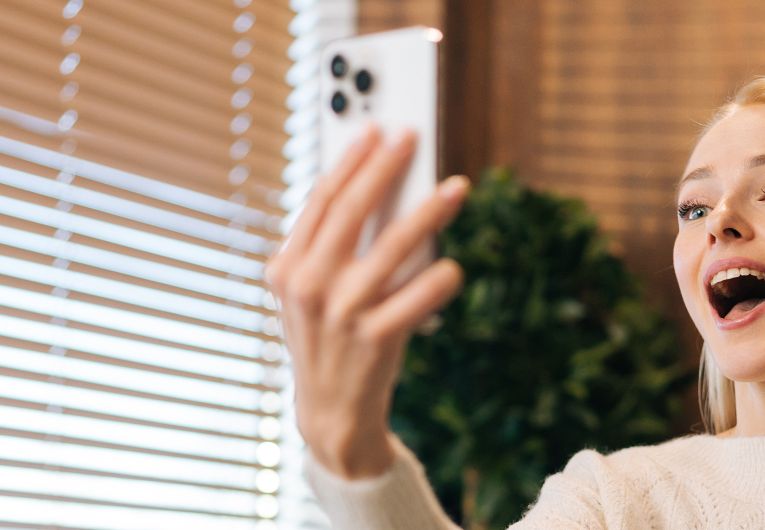 woman waving to video on mobile phone