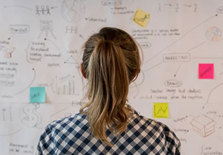 Woman looking at board covered in sticky notes
