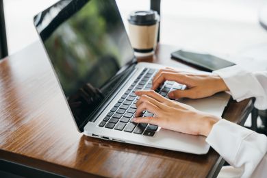 woman's hands typing on laptop