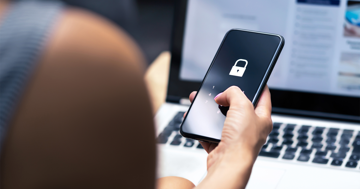 Female holding phone with security lock  in front of computer screen