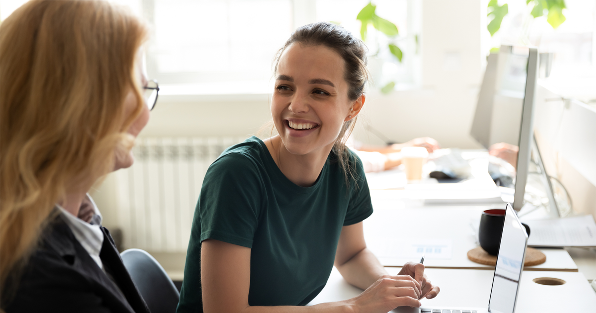 Happy smiling female trainee discussing business ideas with adult trainer