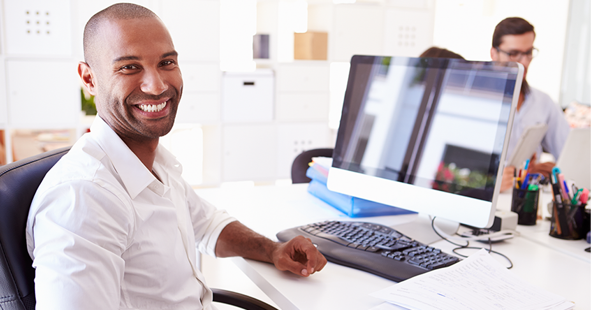 Businessman At Computer In Office smiling