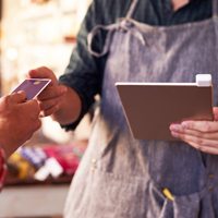 Two people at the point of sale. One person is handing over a credit card for payment.